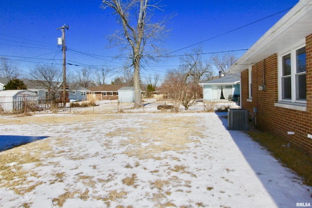 yard covered in snow featuring cooling unit, an outdoor structure, and a residential view