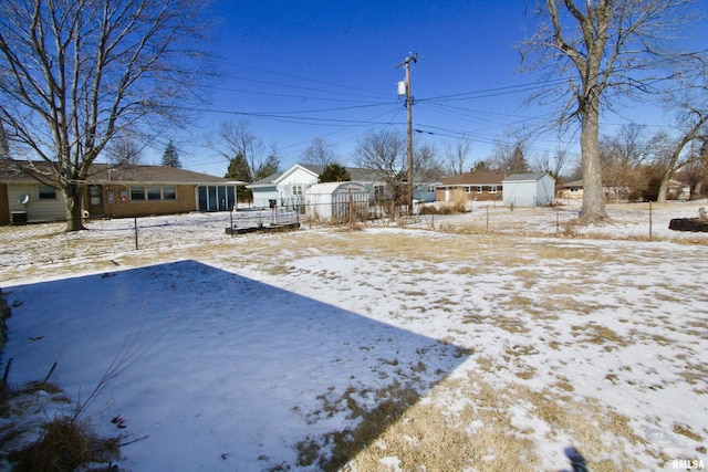 yard layered in snow featuring a residential view and fence