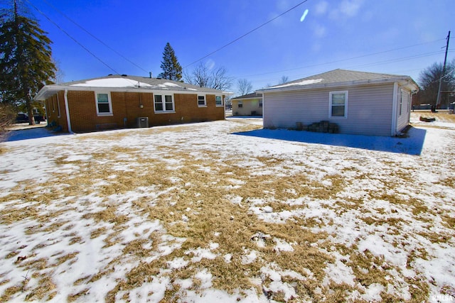 snow covered rear of property with brick siding