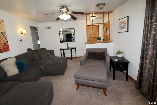 living room featuring baseboards, visible vents, a ceiling fan, and light colored carpet