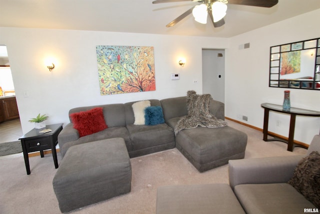 living area with light colored carpet, ceiling fan, and baseboards