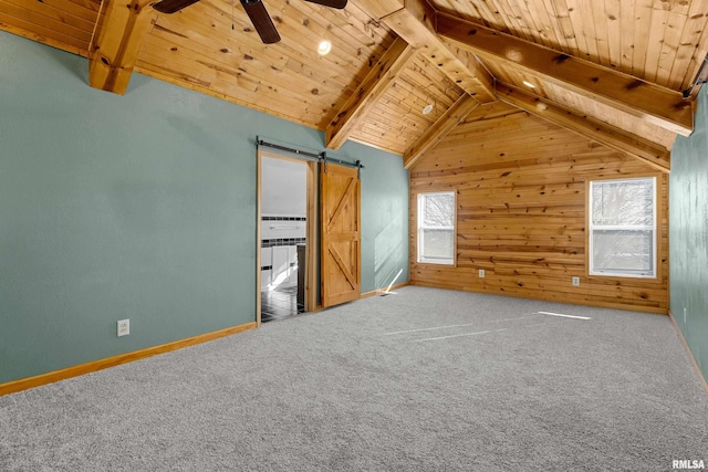 unfurnished bedroom with vaulted ceiling with beams, a barn door, carpet flooring, wood ceiling, and baseboards