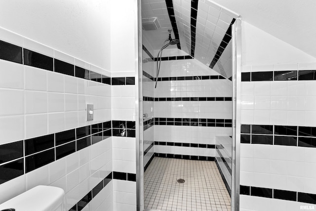 full bathroom with toilet, a stall shower, vaulted ceiling, and tile walls