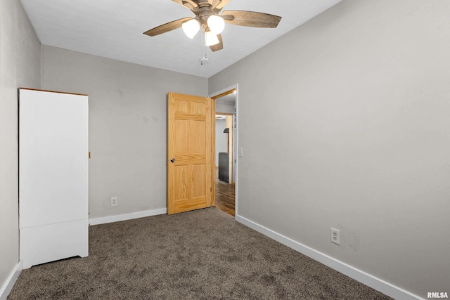 unfurnished bedroom featuring a ceiling fan, dark carpet, and baseboards