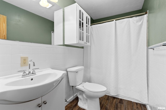 bathroom with toilet, vanity, wood finished floors, and tile walls