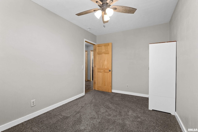 unfurnished bedroom featuring dark colored carpet, ceiling fan, and baseboards