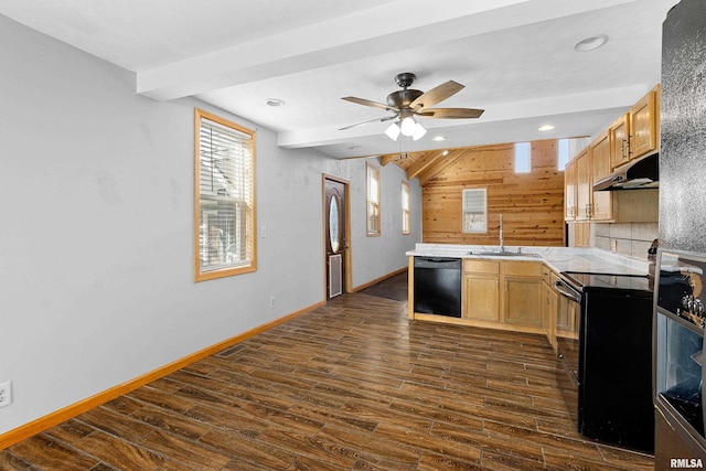 kitchen featuring under cabinet range hood, a sink, light countertops, dark wood-style floors, and black appliances