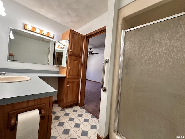 bathroom featuring ceiling fan, vanity, and a shower stall