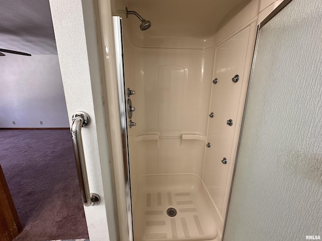 full bath featuring a stall shower, ceiling fan, and baseboards