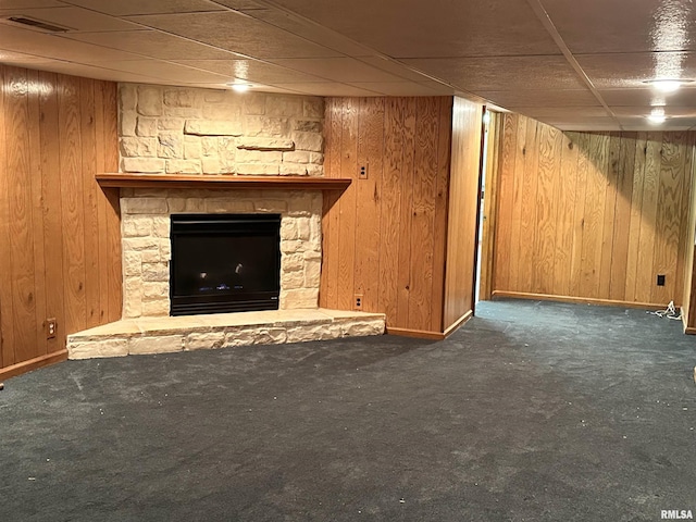 unfurnished living room with dark colored carpet, a fireplace, and wooden walls