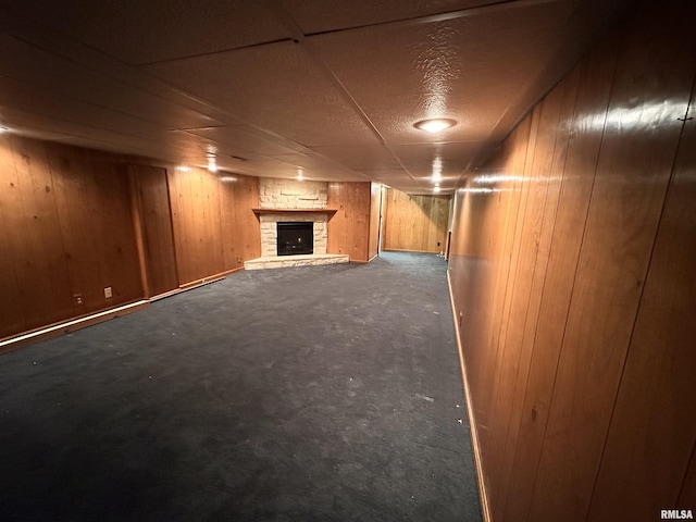 finished basement featuring a stone fireplace and wood walls