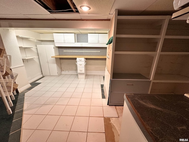 kitchen featuring light tile patterned floors, a drop ceiling, and white cabinets