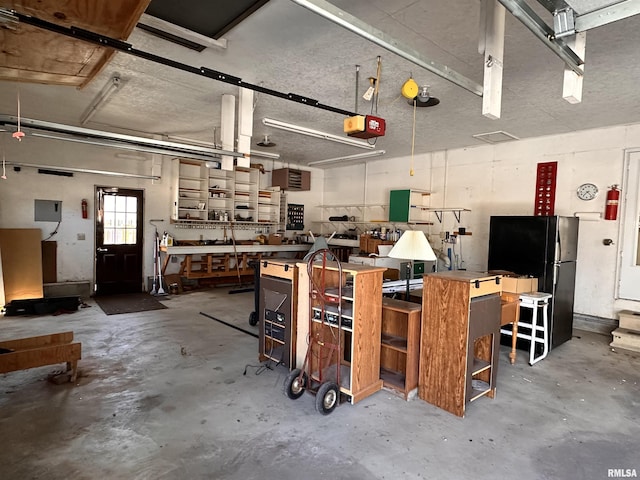 garage with a garage door opener, freestanding refrigerator, and a workshop area