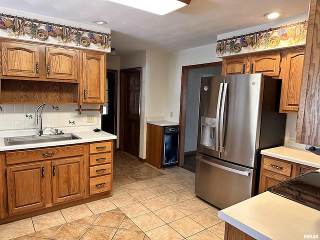 kitchen with light countertops, brown cabinetry, stainless steel fridge, and a sink