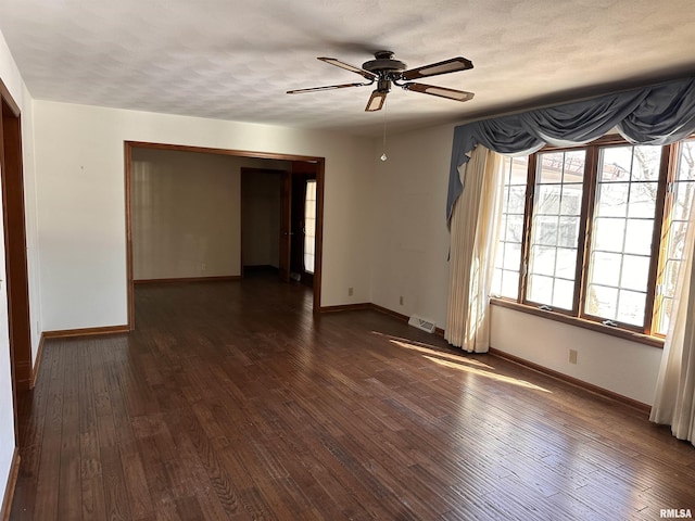 empty room with baseboards, visible vents, dark wood finished floors, and a textured ceiling