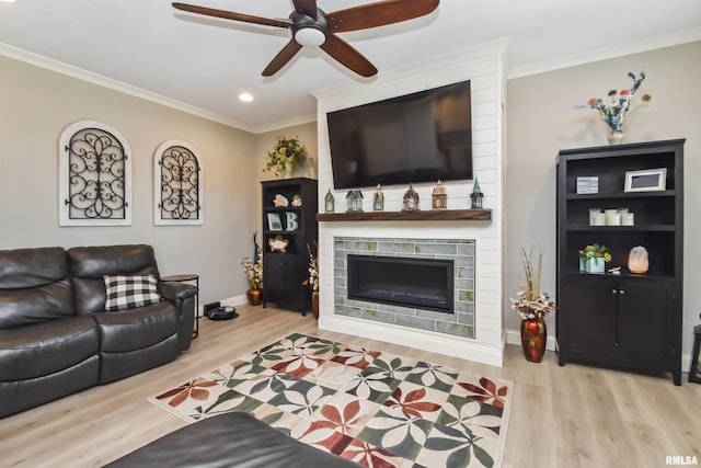 living room featuring a large fireplace, ornamental molding, and light wood finished floors