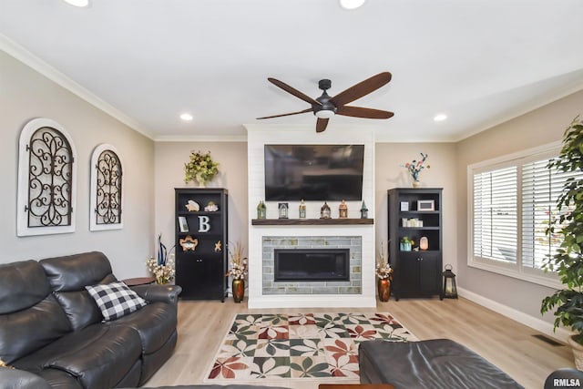 living room featuring visible vents, baseboards, ornamental molding, light wood-type flooring, and a fireplace