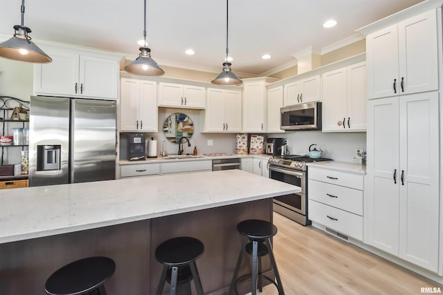 kitchen with light stone counters, appliances with stainless steel finishes, white cabinets, and pendant lighting