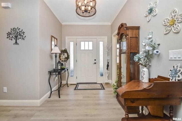 foyer entrance featuring a chandelier, crown molding, light wood-style flooring, and baseboards