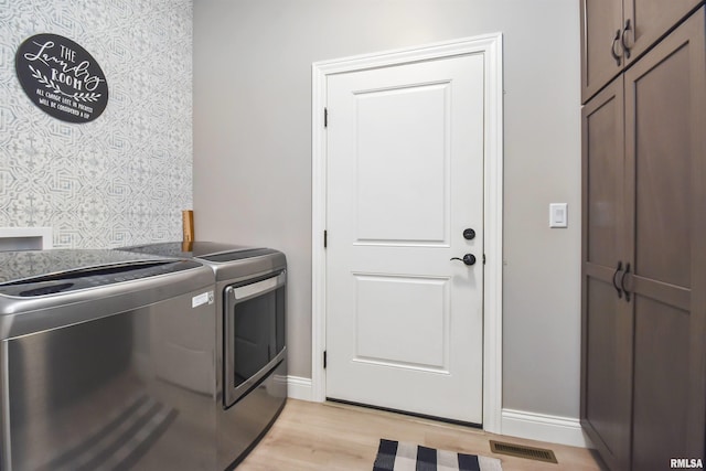 laundry area featuring light wood-type flooring, visible vents, washer and clothes dryer, and baseboards