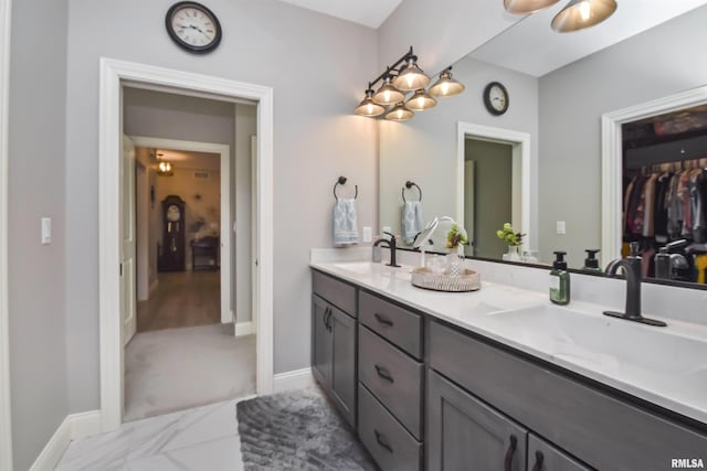 bathroom with a sink, baseboards, and double vanity