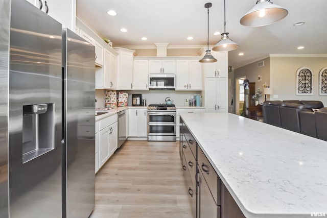 kitchen with stainless steel appliances, white cabinetry, open floor plan, light stone countertops, and decorative light fixtures