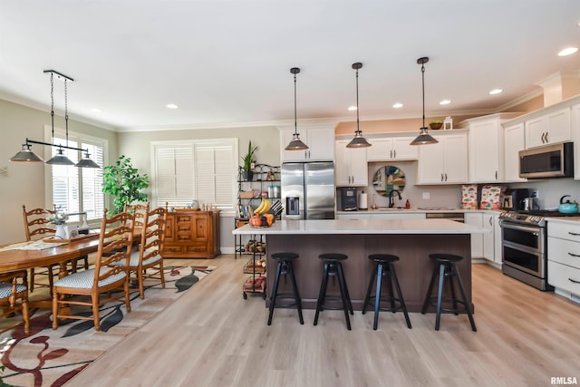 kitchen with appliances with stainless steel finishes, pendant lighting, light countertops, and a center island