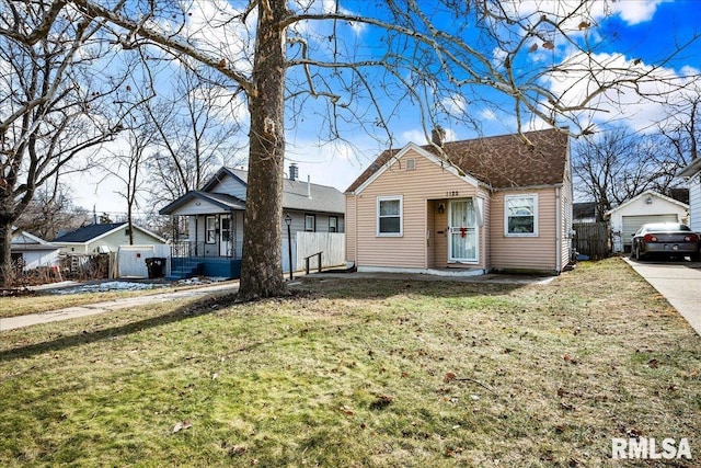 bungalow-style home featuring a garage, a chimney, a front lawn, and an outdoor structure