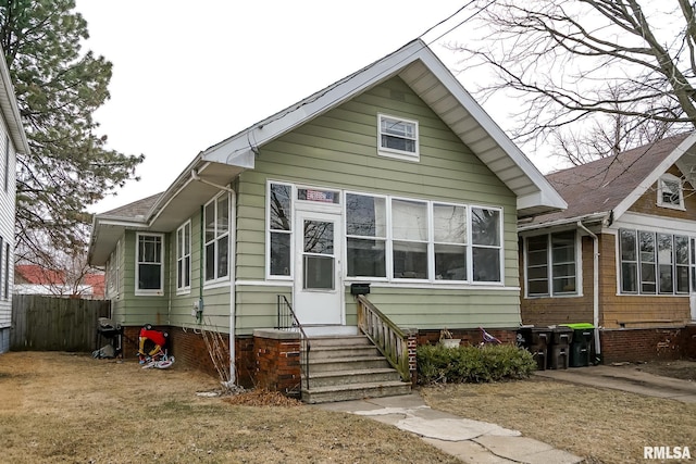 bungalow-style house featuring entry steps, fence, and a front yard