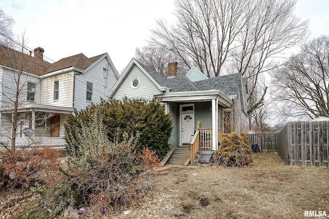 view of front of property featuring a shingled roof, fence, and a chimney