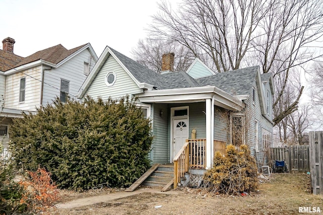 view of front of home featuring a chimney, fence, and roof with shingles