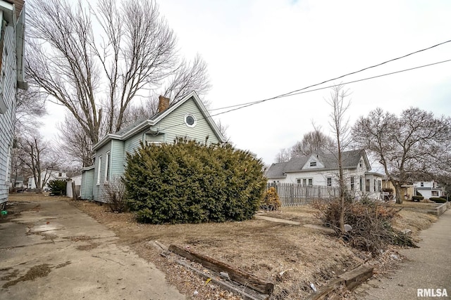 view of property exterior featuring a residential view, fence, and a chimney