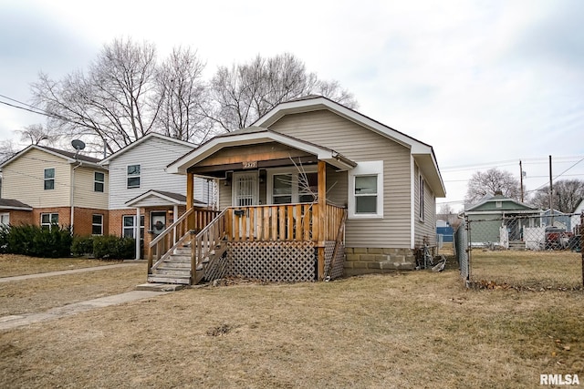 bungalow-style home featuring covered porch, a front yard, and fence