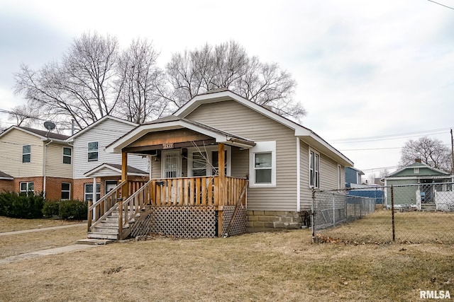 bungalow-style home with a porch, fence, and a front lawn