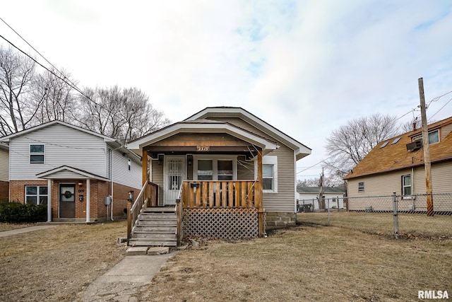 view of front of home featuring covered porch, fence, and a front lawn