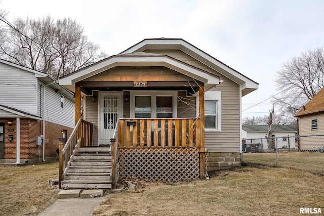 view of front of house featuring a front yard, covered porch, and fence