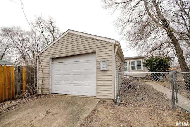 garage featuring concrete driveway and fence