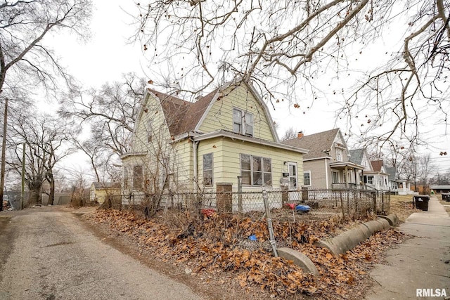 view of side of home featuring roof with shingles, fence, and a gambrel roof