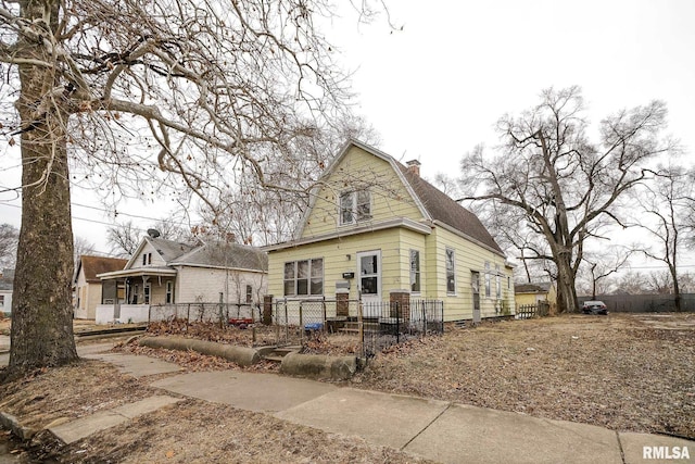 view of front of property with a fenced front yard, a chimney, and a gambrel roof