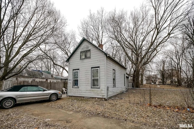 view of side of home featuring fence and a chimney