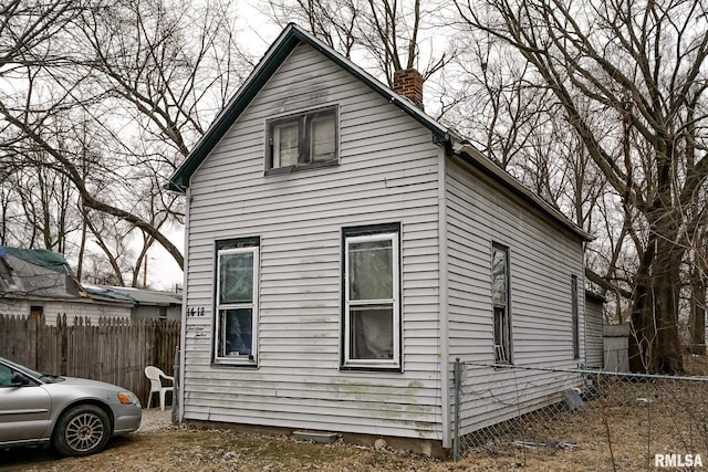 view of property exterior featuring fence and a chimney