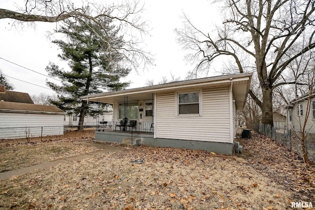 back of property with fence, a porch, and central AC