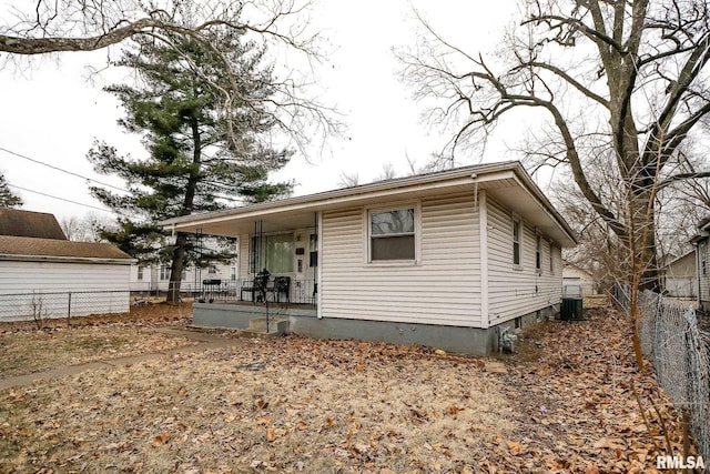 bungalow-style home featuring central air condition unit, covered porch, and fence