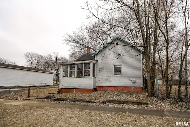 rear view of property featuring a sunroom, a chimney, and fence