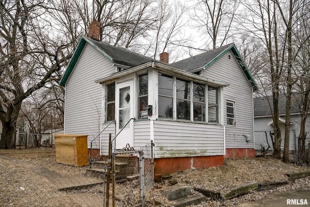 view of front facade with a chimney and fence