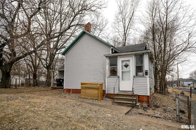 view of front of house featuring entry steps, a chimney, and fence