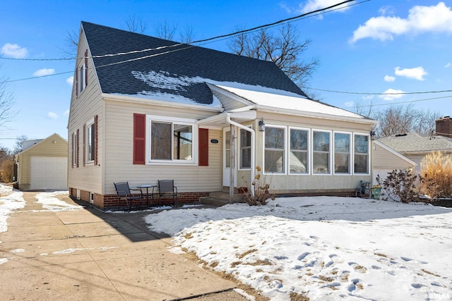 bungalow featuring driveway, roof with shingles, a detached garage, and an outdoor structure