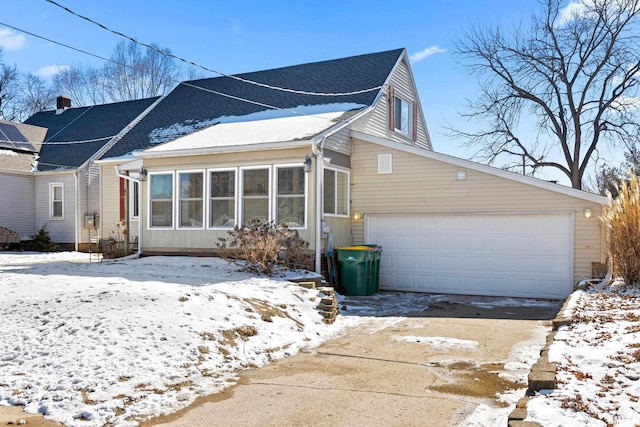 view of snowy exterior with a garage and a shingled roof