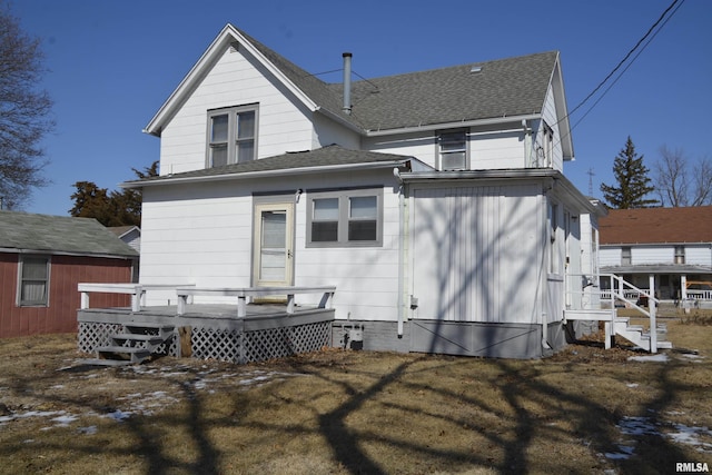 back of house featuring roof with shingles and a wooden deck