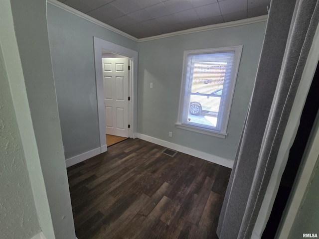 unfurnished room with visible vents, dark wood-style floors, baseboards, and ornamental molding